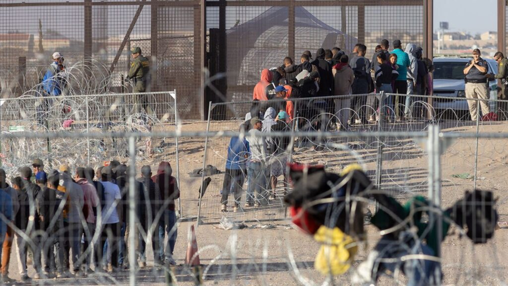 a group of people standing in front of barbed wire fence